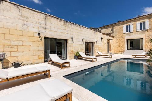 un patio avec une piscine et deux chaises et un bâtiment dans l'établissement La Girondine - Piscine, billard, vigne et estuaire, à Gauriac