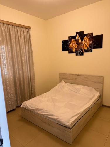a bedroom with a bed with white sheets and flowers on the wall at Home in Pʼarakʼar