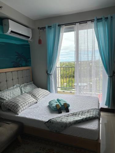 ein Schlafzimmer mit einem Bett mit blauen Vorhängen und einem Fenster in der Unterkunft Sun Drift Studio near airport with Pool and Parking in Lapu Lapu City