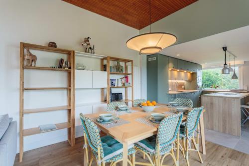 une cuisine et une salle à manger avec une table et des chaises en bois dans l'établissement Maison Lamina - Welkeys, à Anglet