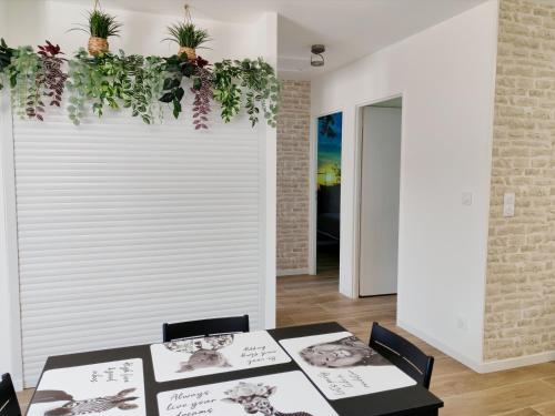 a dining room with two tables and plants on the wall at Le temps de la pause 1 in Cepoy