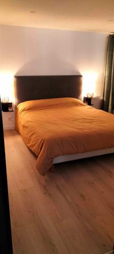 un lit dans une chambre avec deux lampes et un parquet dans l'établissement Appartement, en bord du GR34, à Hillion