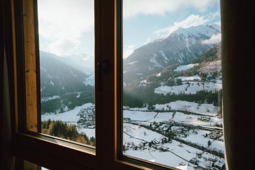 a window with a view of a snow covered mountain at Lahnerhof Chalets in Lutago