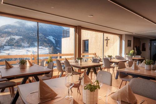 a restaurant with tables and chairs and a large window at Lahnerhof Chalets in Lutago