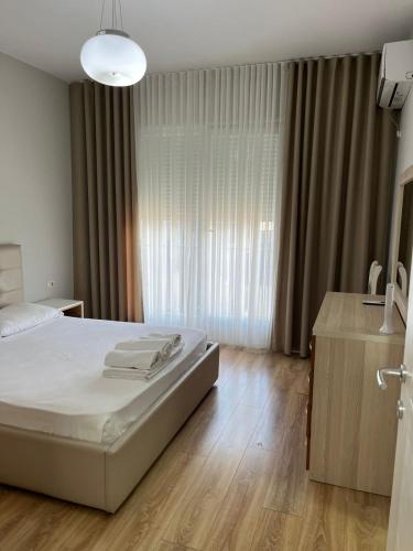 a bedroom with a bed and a large window at Liqeni New Apartament in Tirana