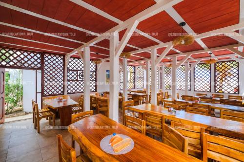 a restaurant with wooden tables and wooden chairs at Caribbean Town Tolu in Tolú