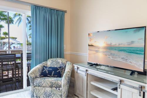 a living room with a flat screen tv and a chair at Crystal Waters in Duck Key