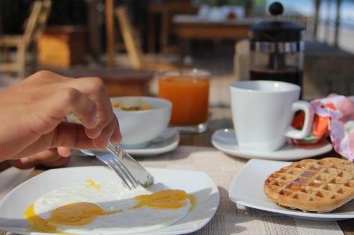a person eating eggs and waffles on a table at Baja Canoas Hotel in Canoas De Punta Sal