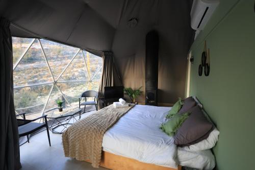 a bedroom with a bed and a large window at Nomaddome Glamping Hotel in Mishmish