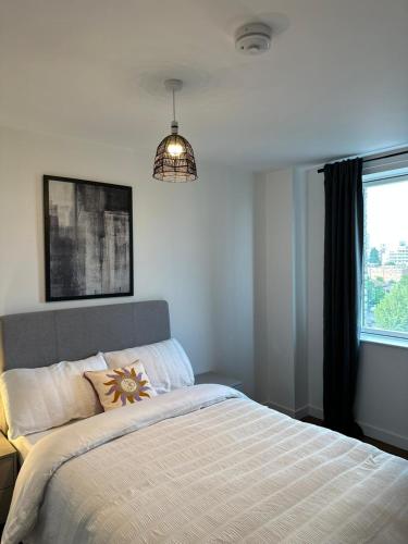 a bedroom with a bed with a flower pillow on it at Amazing 2 Bed Flat With City Views in Barking