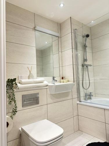 a bathroom with a shower and a toilet and a sink at Amazing 2 Bed Flat With City Views in Barking