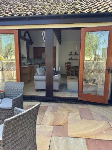 a patio with sliding glass doors and a living room at Elm Barn in Diss