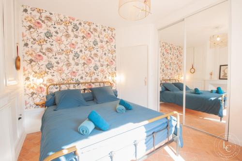 une chambre avec un lit bleu et un miroir dans l'établissement Maison raffinée 4 étoiles - Terrasse et Accès train Paris, à Meung-sur-Loire