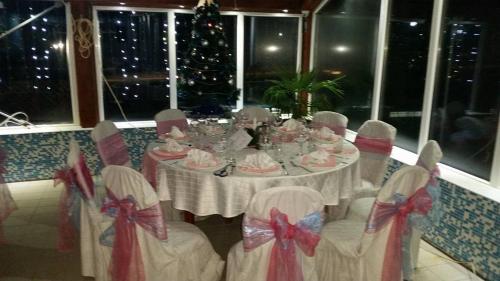 a dining room table with chairs and a christmas tree at Sokoterme Hotel in Soko Banja