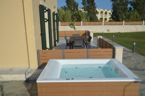 a hot tub sitting on a patio with two benches at Issos House in Agios Georgios