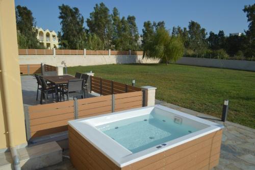 a jacuzzi tub in a backyard with a table at Issos House in Agios Georgios