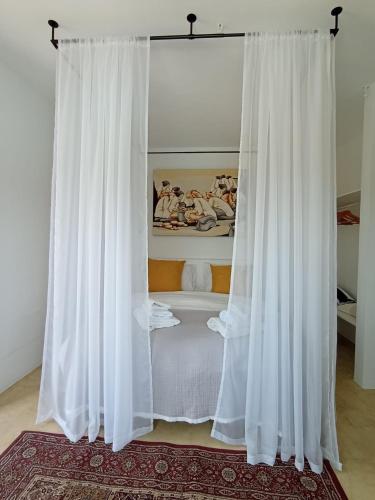 a white bed with white curtains in a room at The Peak House in Carovigno