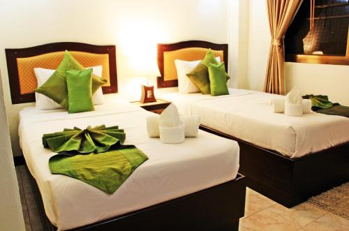 two beds in a hotel room with green pillows at Namkhong Riverside in Chiang Khong