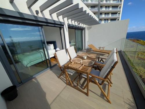 a patio with a table and chairs on a balcony at Breathtaking Oceanfront Living, Sunset Facing 3-Bedroom Flat in Acqua Residences in Funchal