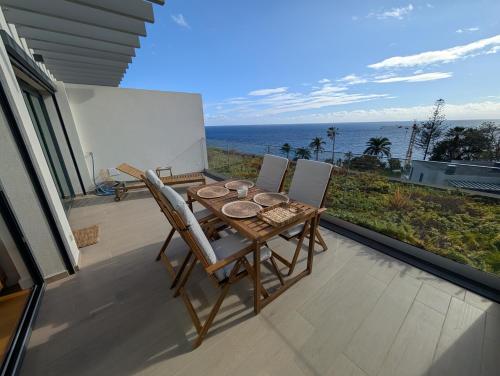 a table and chairs on a balcony with the ocean at Breathtaking Oceanfront Living, Sunset Facing 3-Bedroom Flat in Acqua Residences in Funchal
