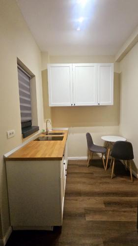 a kitchen with white cabinets and a table and a sink at Little Bucharest downtown apartments Romana in Bucharest