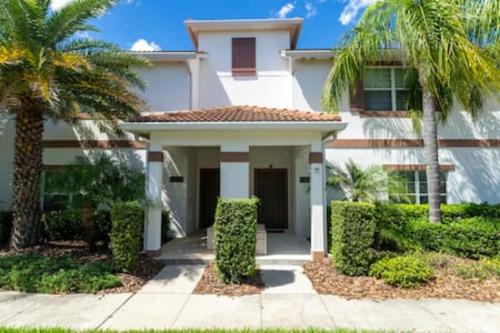 a white house with palm trees in front of it at 4 Bedrooms3 Bathrooms at Storey Lake Resort in Kissimmee