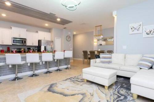 a living room with white furniture and a kitchen at 4 Bedrooms3 Bathrooms at Storey Lake Resort in Kissimmee