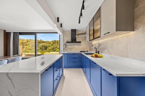 ザダルにあるLuxury Pool Seaside Apartments Zadarのキッチン(青いキャビネット付)、大きな窓