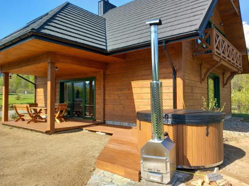 a log cabin with a grill in front of it at Chata pod Jelenim Skokiem in Cisna