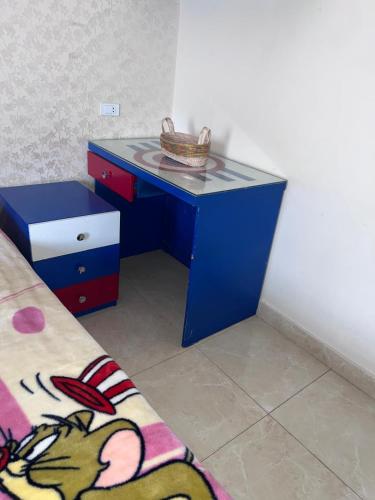 Un escritorio azul con una canasta encima, al lado de una cama. en single room shared bathroom, en El Cairo