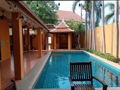 a swimming pool with two chairs and a gazebo at Jomtien 4BR golden villa in Jomtien Beach