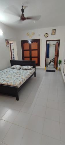 a bedroom with a bed and a white tile floor at Thillai Aura Homestay in Chidambaram