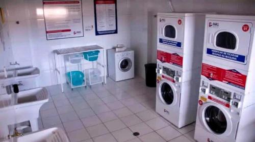a laundry room with three washing machines and a sink at 1027 Apartamento Luxuoso! in Ribeirão Preto