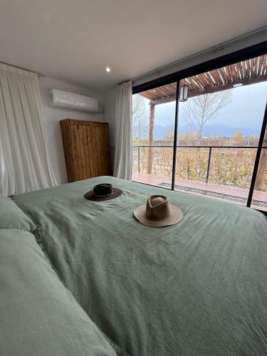 two hats on a bed in a bedroom with a window at La Viñita Wine Lodge in La Consulta