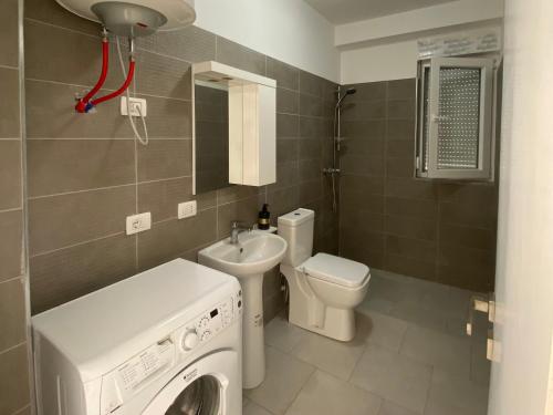 a bathroom with a washing machine and a toilet at BlueWaveapartments 2 in Shëngjin