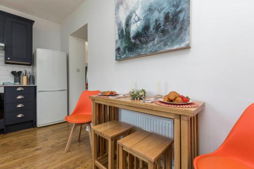 a kitchen with a table and two orange chairs at Well-equipped Apartment at Westerlands Farm in Graffham