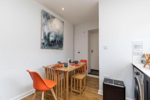 a kitchen with a small wooden table and orange chairs at Well-equipped Apartment at Westerlands Farm in Graffham