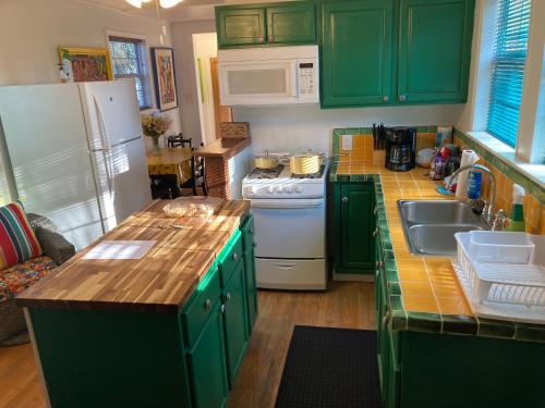 a kitchen with green cabinets and a white refrigerator at Green garden view in New Orleans