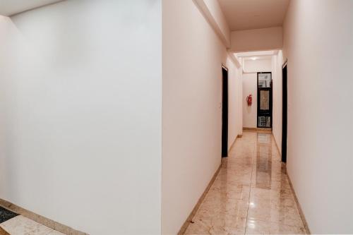 a corridor in a building with white walls and tile floors at Hotel O Royal galaxy suites in Bengaluru