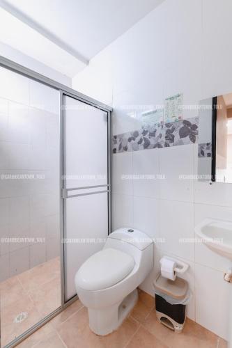 a white bathroom with a toilet and a sink at Caribbean Town Tolu in Tolú