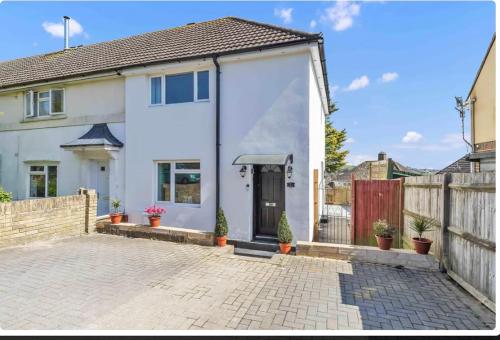 a white house with a door and a fence at Kemptown Corner with Free Parking in Brighton & Hove