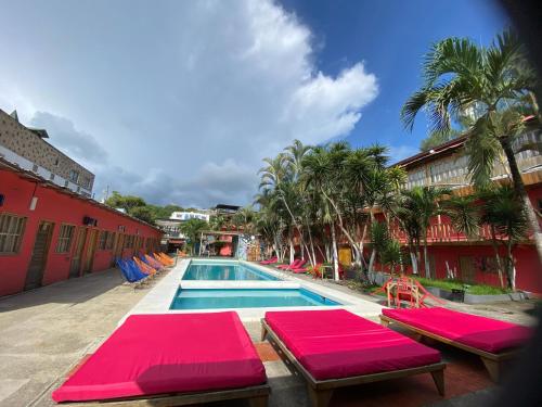 a swimming pool with red cushioned chairs next to a building at Hotel Montañita in Montañita