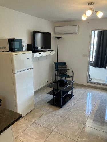 - une cuisine avec une télévision et une chaise dans la chambre dans l'établissement Studio des Quilles, à Sète