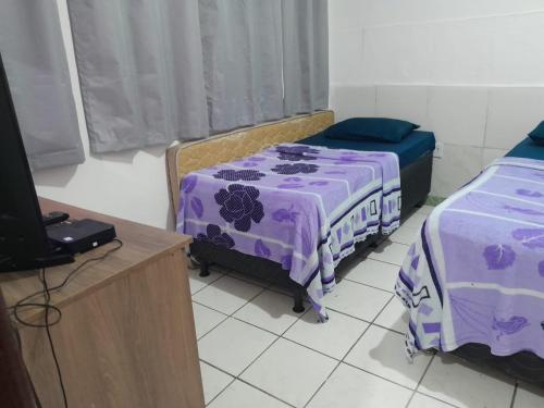 a room with two beds and a tv in it at Casa e Kitnet - Praia Grande Centro in Arraial do Cabo