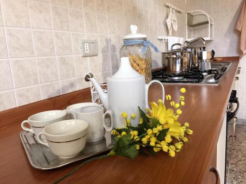 a kitchen counter with cups and flowers on a tray at Pizzicarella by Palazzo Refolo in Martano