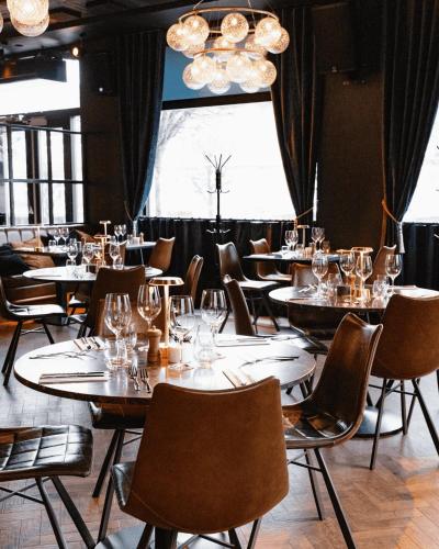 a dining room with tables and chairs and a window at Hotel Oleana in Bergen