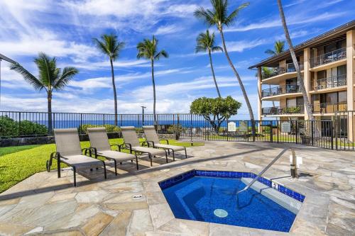 a patio with chairs and a swimming pool and a building at Kona Makai Private Tropical Suites with Pool in Kailua-Kona