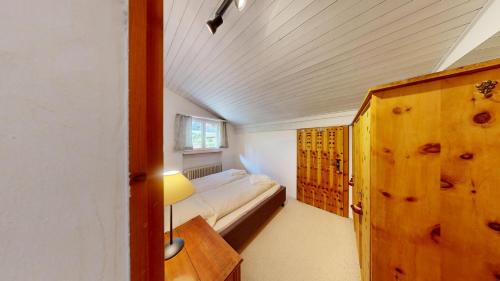 a small bedroom with a bed and a wooden cabinet at Apartment Suot Larschs in Samedan