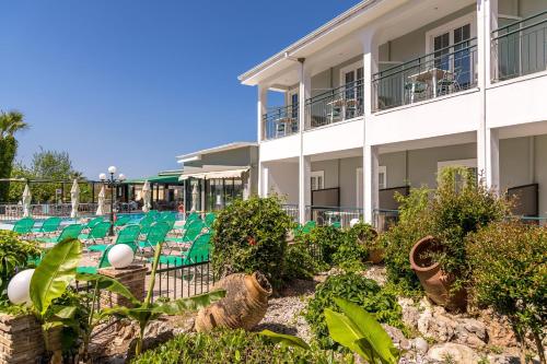a resort with green chairs and a building at Sofia's Hotel in Kalamaki