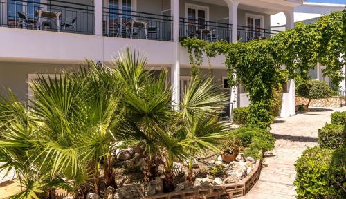 a building with palm trees and plants in front of it at Sofia's Hotel in Kalamaki